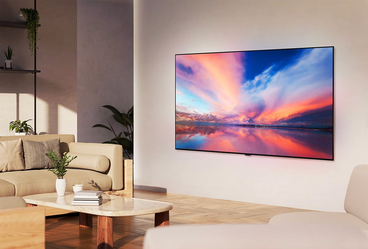 Μία LG OLED TV, στραμμένη 45 μοίρες στα αριστερά, απεικονίζοντας ένα όμορφο ηλιοβασίλεμα με μια βάρκα σε μια λίμνη, καθώς η τηλεόραση συνδέεται σε ένα LG Soundbar με τον βραχίονα Synergy σε ένα μινιμαλιστικό σαλόνι.